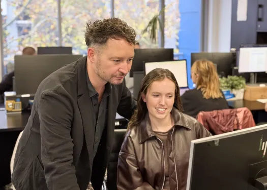 Two Online Marketing Gurus account managers reviewing campaign data together on screen in the agency office.