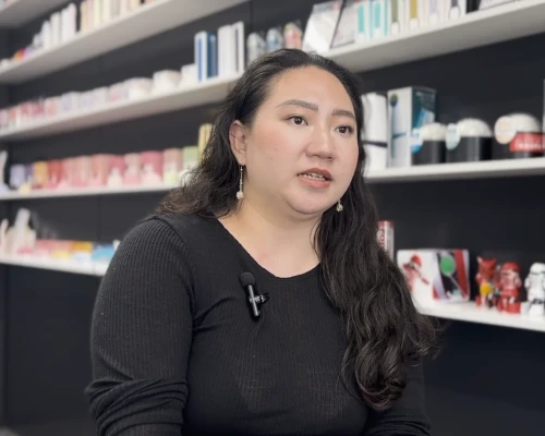 A representative from TENGA, an ecommerce client of Online Marketing Gurus, being interviewed on camera in front of shelves displaying the company's products