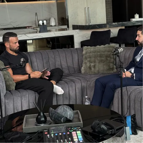 Andrew Raso, founder of Online Marketing Gurus, recording a podcast episode with a guest on a grey lounge setup at the OMG content studio.