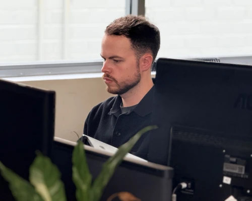 An Online Marketing Gurus SEO link building specialist focused on his work at a multi-monitor desk in Dallas
