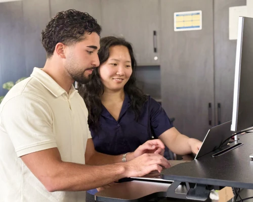 Two Online Marketing Gurus technical SEO consultants working together at a standing desk, reviewing a site on screen.