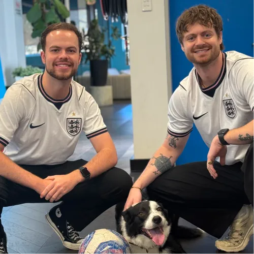 Dan and Adam in England football shirts with the office dog at OMG