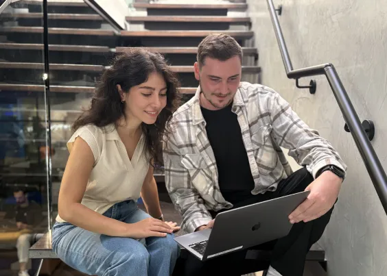 Two OMG Academy attendees reviewing course material on a laptop