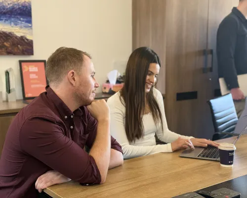 Two OMG paid media specialists collaborating on a Google Shopping campaign at a laptop in the office