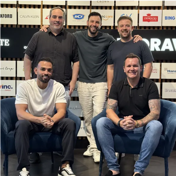 OMG's Australia, US and Dubai leadership team in front of a wall of client brand logos.