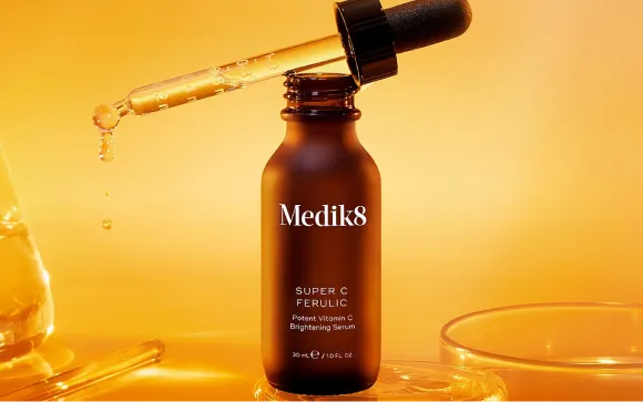 Medik8 Super C Ferulic vitamin C brightening serum with dropper against a golden background